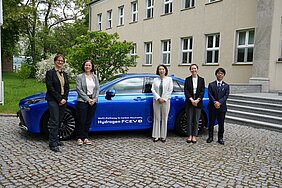 Group photo in front of a blue hydrogen-powered vehicle