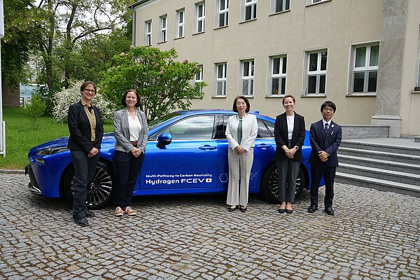 Group photo in front of a blue hydrogen-powered vehicle