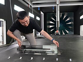 Dr. Long Chen beugt sich über ein Stallmodell, dass in einem Windkanal steht.