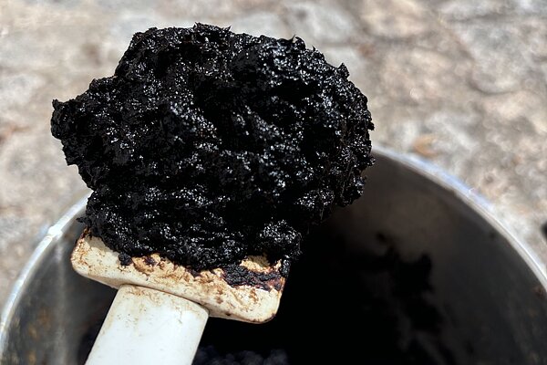 Schwarzer, künstlicher Torf auf einem großen Spatel