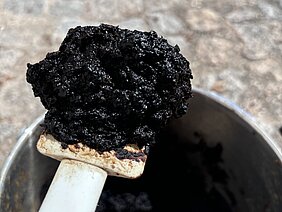 Schwarzer, künstlicher Torf auf einem großen Spatel