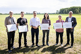 Gruppenbild mit Projektpartnern, die Förderbescheid halten