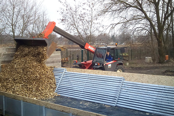 Aufschütten der Miete mit feuchten Holzhackschnitzeln auf einer Versuchsplattform und innenliegendem Lüftungskanal (Foto: Lühr/ATB)