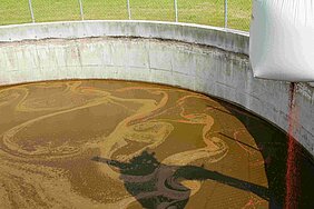 Rotes Kalkstickstoffgranulat rieselt in Gärresttank.