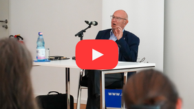 Dr. Patermann hält den Vortrag, Youtube Symbol im Vordergrund