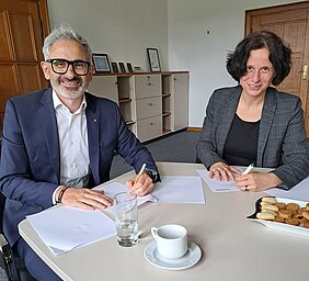Die Direktor*innen unterschreiben den Vertrag.