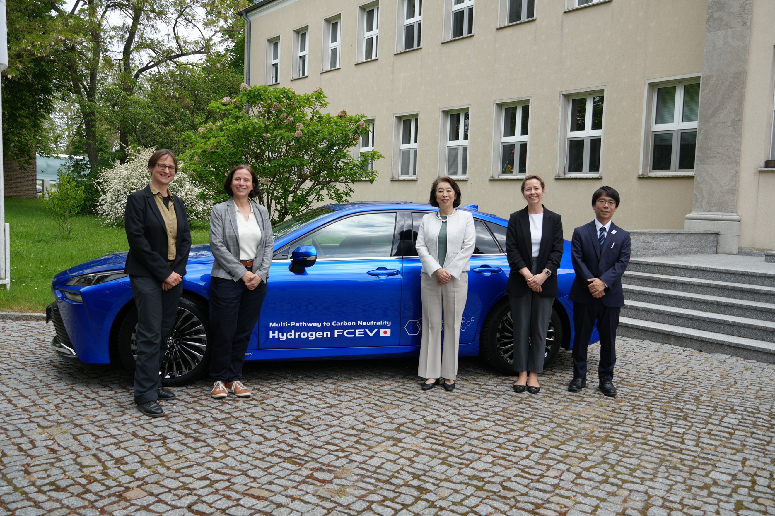 Group photo in front of a blue hydrogen-powered vehicle